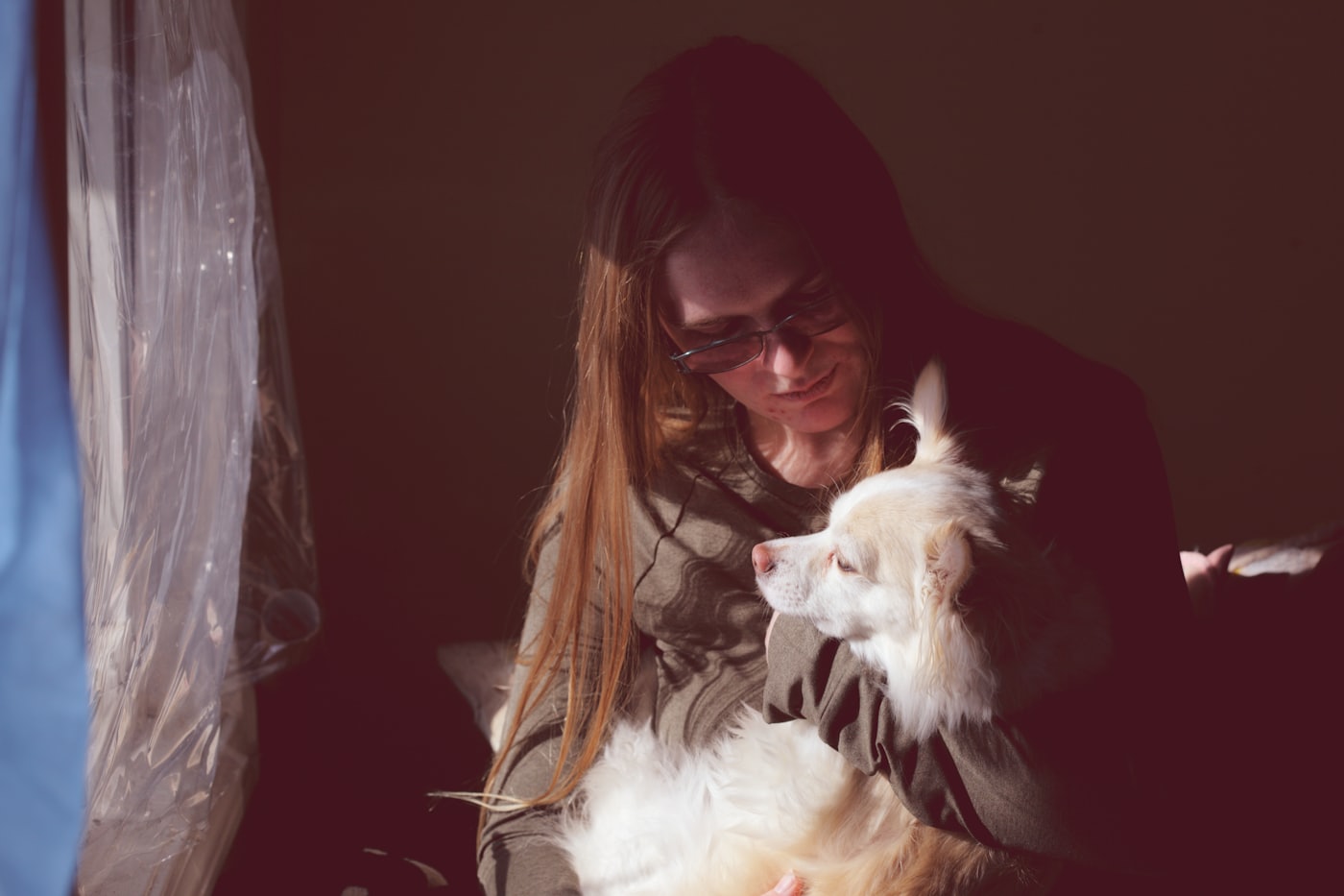 A woman kissing her dog in golden light